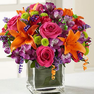 Birthday blooms that are ready to get your recipient's special day started, this flower bouquet is bright, happy, and ready to celebrate! Hot pink roses and orange Asiatic Lilies are vibrant and fun surrounded by purple Peruvian Lilies, hot pink mini carnations, green button poms, purple statice, and an assortment of lush greens. Accented with assorted curling ribbons to give it that party feels and presented in a clear glass cubed vase lined with ti leaf green material for added beauty, this unforgettable birthday bouquet is that ultimate surprise that will make them feel the love on their big day.

STANDARD bouquet includes 11 stems.
Approximately 10H x 10W.
C Quantity Color Description
2 Hot Pink 50 cm Standard Rose
1 Orange Asiatic Lily
3 Purple Alstroemeria
2 Green Button Pom
2 Hot Pink Miniature Carnation
1 Purple Filler - Sinuata Statice
2 Green Green - Leather Leaf
1 Green Green - Pittosporum
0.33 Green Green Flexible Leaf Material
1.5 Curling Ribbon (yds.)
0.33 Green Florist Foam Brick

DELUXE bouquet includes 15 stems.
Approximately 11H x 11W.
C Quantity Color Description
4 Hot Pink 50 cm Standard Rose
1 Orange Asiatic Lily
3 Purple Alstroemeria
2 Green Button Pom
3 Hot Pink Miniature Carnation
2 Purple Filler - Sinuata Statice
2 Green Green - Leather Leaf
1 Green Green - Pittosporum
0.33 Green Green Flexible Leaf Material
1.5 Curling Ribbon (yds.)
0.33 Green Florist Foam Brick

PREMIUM bouquet includes 19 stems.
Approximately 12H x 12W.
C Quantity Color Description
5 Hot Pink 50 cm Standard Rose
2 Orange Asiatic Lily
4 Purple Alstroemeria
3 Green Button Pom
3 Hot Pink Miniature Carnation
2 Purple Filler - Sinuata Statice
2 Green Green - Leather Leaf
1 Green Green - Pittosporum
0.66 Green Green Flexible Leaf Material
3 Curling Ribbon (yds.)
0.5 Green Florist Foam Brick